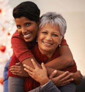 A senior woman receiving a hug from her daughter.