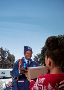 Letter Carrier delivering a package to a customer.